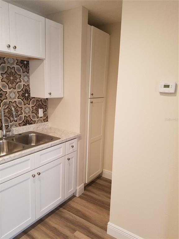 A kitchen features white cabinets, a patterned tile backsplash, a double sink, and wood-look flooring — 505 BOXELDER AVENUE, ALTAMONTE SPRINGS, FL