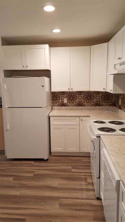A kitchen features white cabinets, a white refrigerator, a patterned backsplash, and wood-look flooring — 505 BOXELDER AVENUE, ALTAMONTE SPRINGS, FL