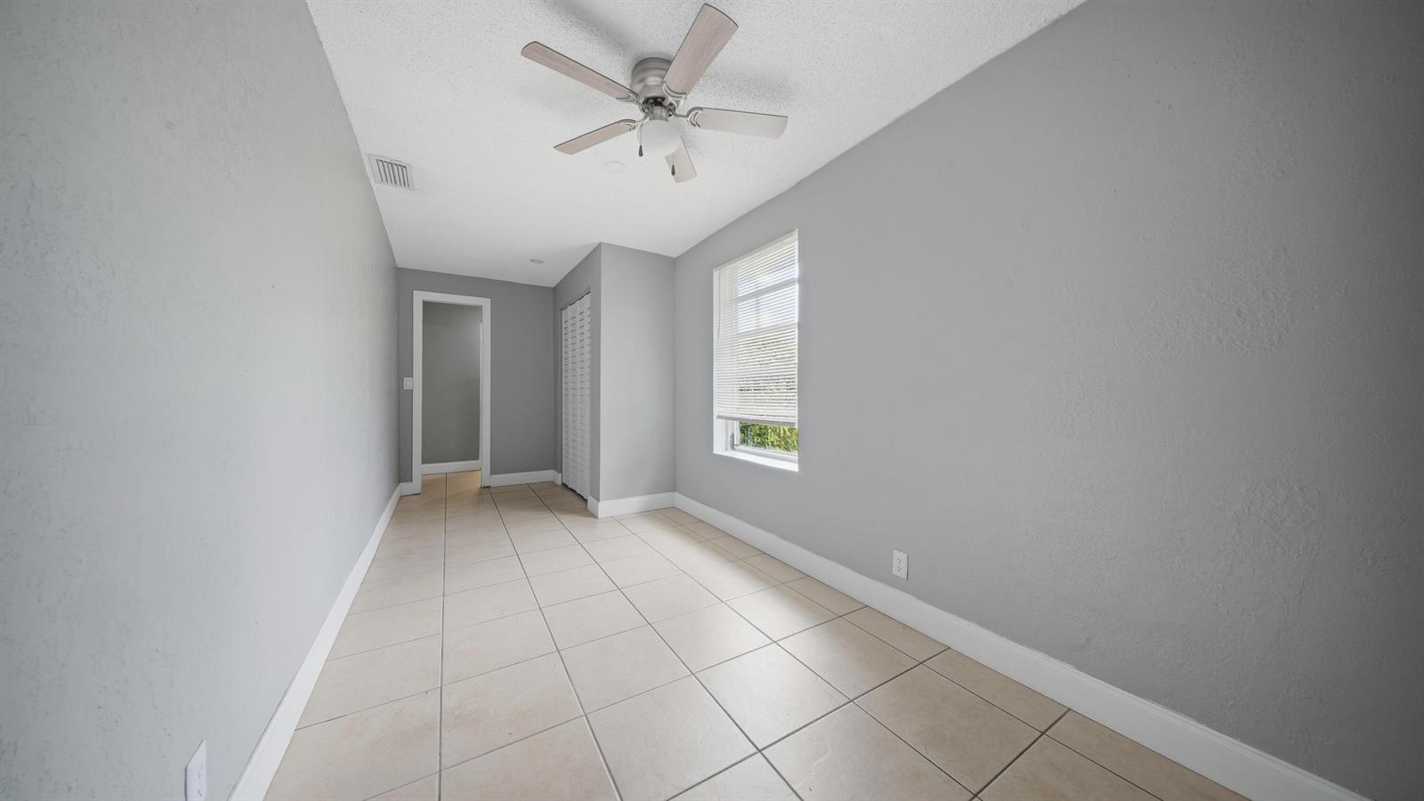 An empty room with light gray walls, tile flooring, a ceiling fan, and a window — 4681 SW 43rd Terrace # 2, Dania Beach FL 33314, DANIA BEACH, FL