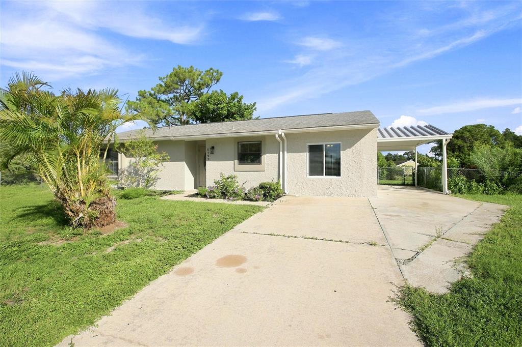 A single-story house with a concrete driveway, a carport, and a palm tree in front — 5799 FRAN COURT, NORTH PORT, FL