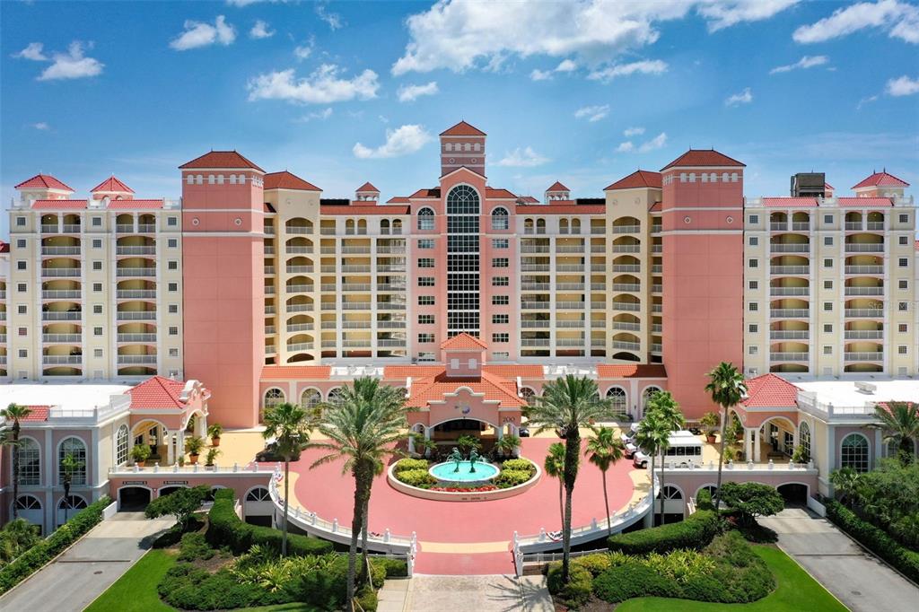 An aerial view of a large, multi-story pink hotel with a circular driveway and fountain — 200 OCEAN CREST DRIVE UNIT 913, PALM COAST, FL
