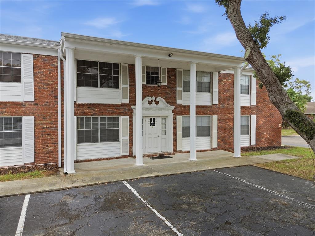 A two-story brick apartment building features a white columned porch and a central entrance — 4507 9TH STREET W. UNIT I3, BRADENTON, FL