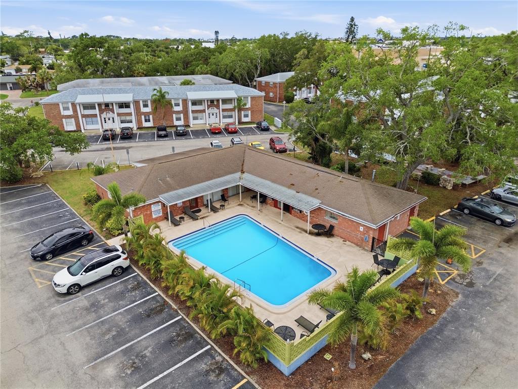 An aerial view shows a swimming pool surrounded by a patio, palm trees, and parking — 4507 9TH STREET W. UNIT I3, BRADENTON, FL