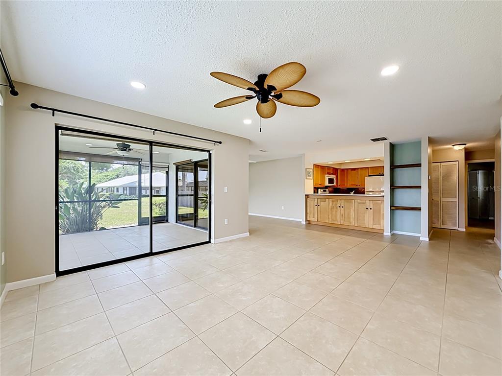 A living room with tile floors, a ceiling fan, and a sliding door to a lanai — 2733 COUNTRYSIDE BOULEVARD UNIT 105, CLEARWATER, FL