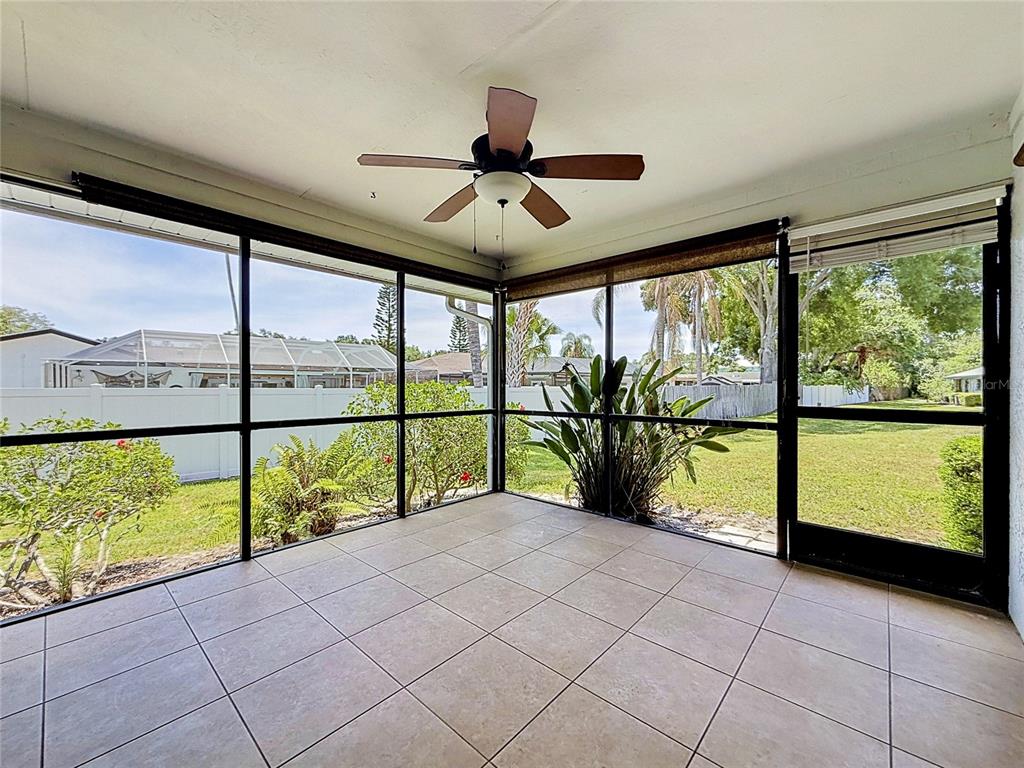 A screened-in porch with tile flooring, a ceiling fan, and views of a backyard — 2733 COUNTRYSIDE BOULEVARD UNIT 105, CLEARWATER, FL