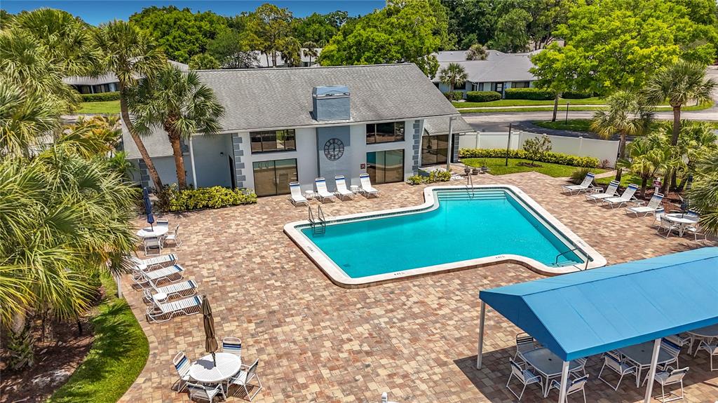 An aerial view of a swimming pool area with lounge chairs and a covered patio — 2733 COUNTRYSIDE BOULEVARD UNIT 105, CLEARWATER, FL