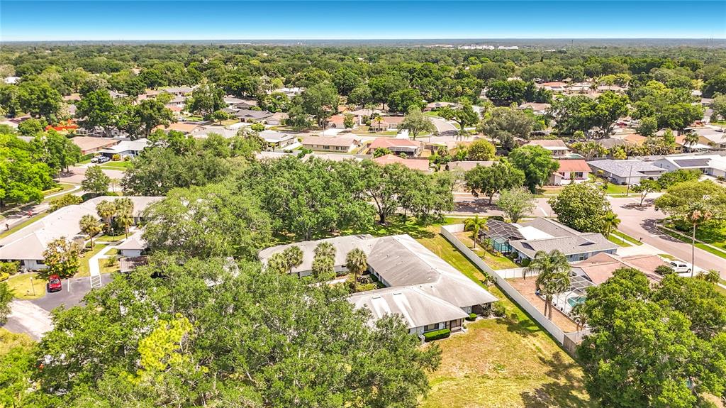 An aerial view shows a single-story residential building surrounded by trees and suburban homes — 2733 COUNTRYSIDE BOULEVARD UNIT 105, CLEARWATER, FL