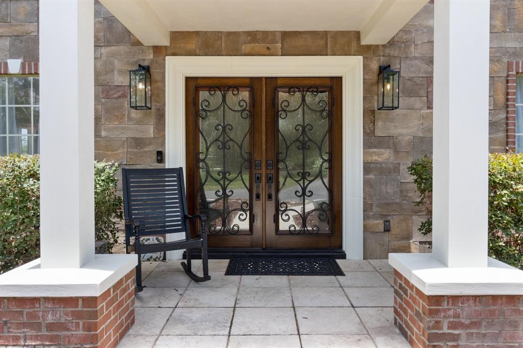 A front porch features a double wooden door with iron scrollwork, stone walls, and columns — 2065 SW 37TH STREET ROAD, OCALA, FL