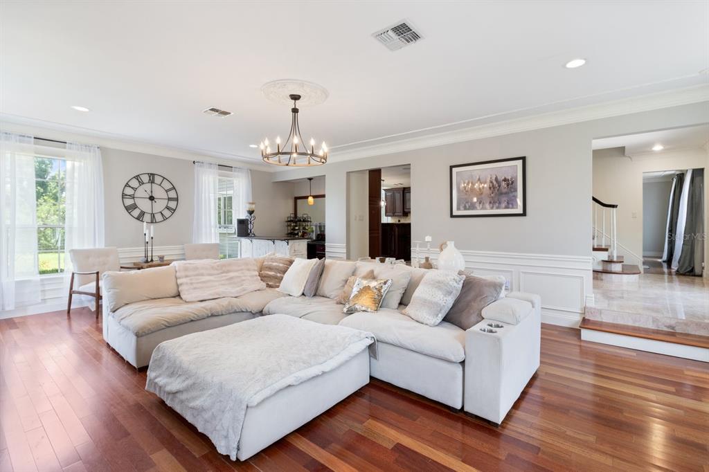 A spacious living room features a large sectional sofa, hardwood floors, and a chandelier — 2065 SW 37TH STREET ROAD, OCALA, FL
