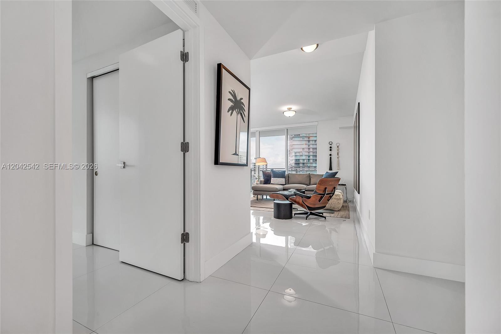 A white hallway with glossy tile floors leads into a living room with city views — 1080 Brickell Ave # 1601, Miami FL 33131, MIAMI, FL