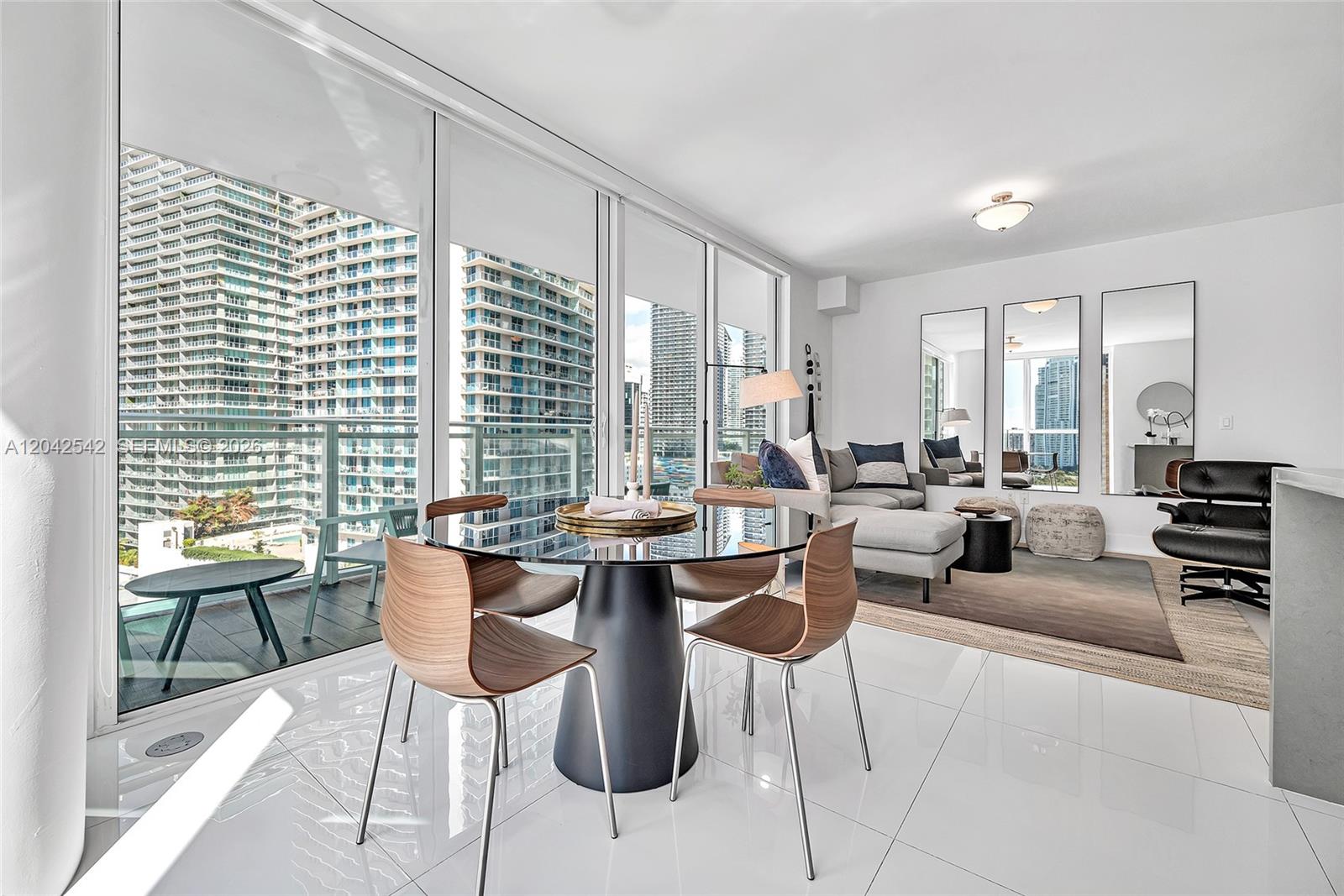 A modern dining and living area features floor-to-ceiling windows overlooking high-rise city buildings — 1080 Brickell Ave # 1601, Miami FL 33131, MIAMI, FL