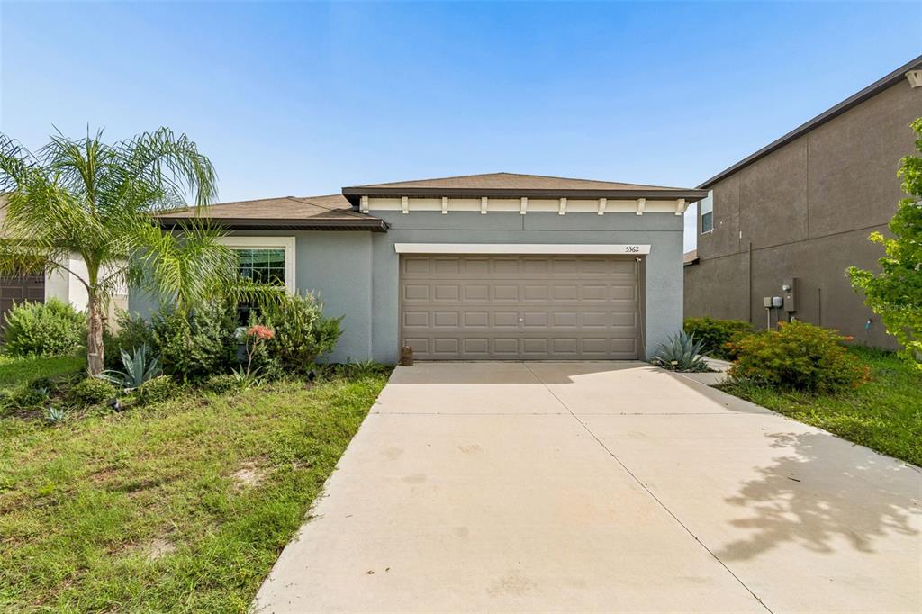 A single-story house with a gray stucco exterior, a two-car garage, and a concrete driveway — 5362 BLUE HORIZON WAY, WIMAUMA, FL