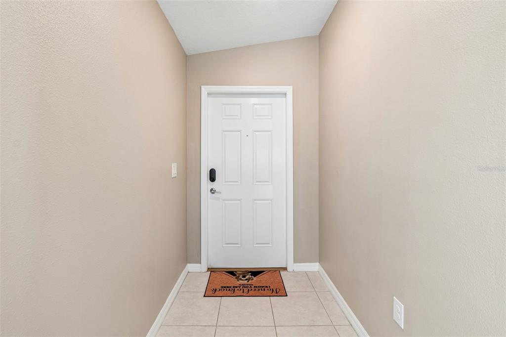 A small entryway features beige walls, light tile flooring, and a white front door — 5362 BLUE HORIZON WAY, WIMAUMA, FL