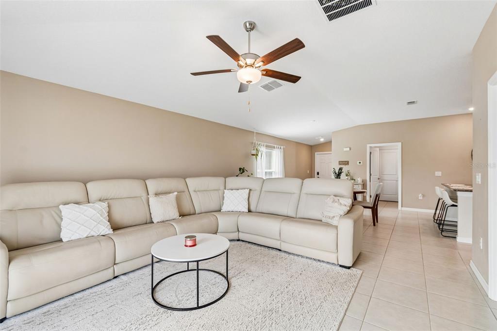 A living room features a large beige sectional sofa, a round coffee table, and tile flooring — 5362 BLUE HORIZON WAY, WIMAUMA, FL