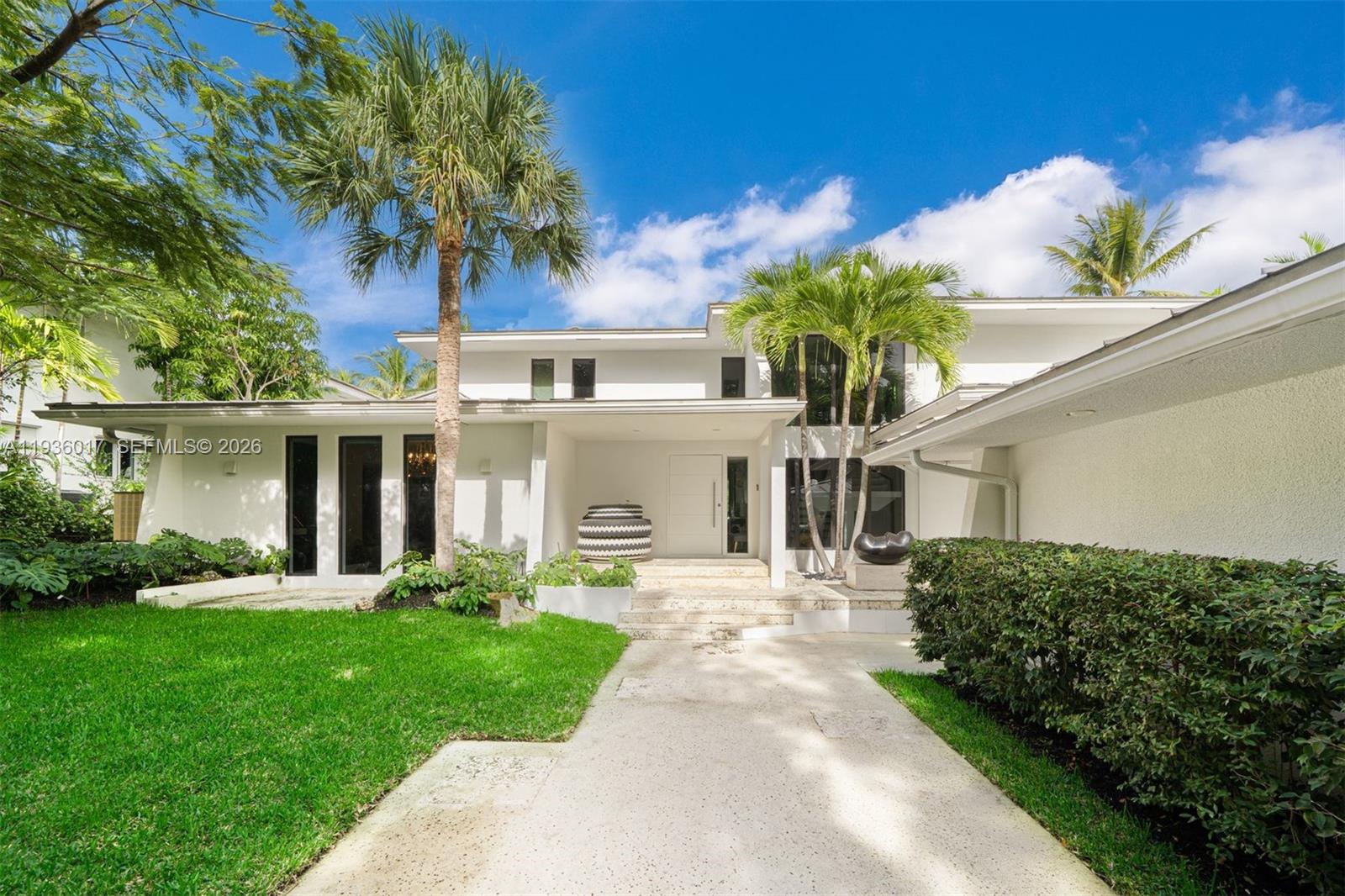A modern white two-story house features a palm-lined entrance with a concrete walkway — 121 Knollwood Drive, Key Biscayne FL 33149, KEY BISCAYNE, FL