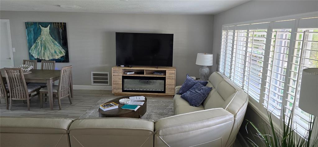 A living room features a light-colored sectional sofa, a television console with a fireplace, and tile flooring — 6351 3RD PALM POINT, ST PETE BEACH, FL