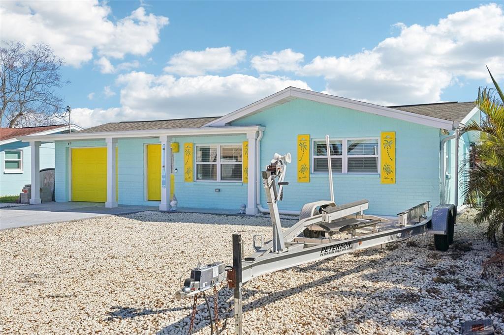 A light blue house with yellow accents and a boat trailer parked in the yard — 13700 LESLIE DRIVE, HUDSON, FL