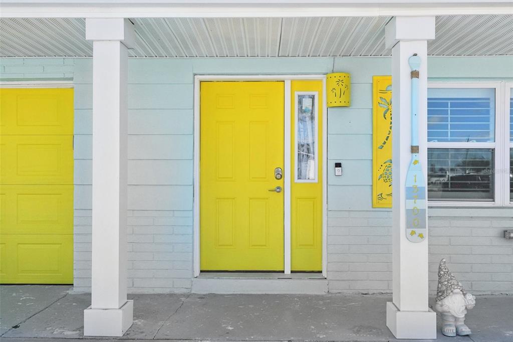 A bright yellow front door and matching garage door on a light blue house exterior — 13700 LESLIE DRIVE, HUDSON, FL