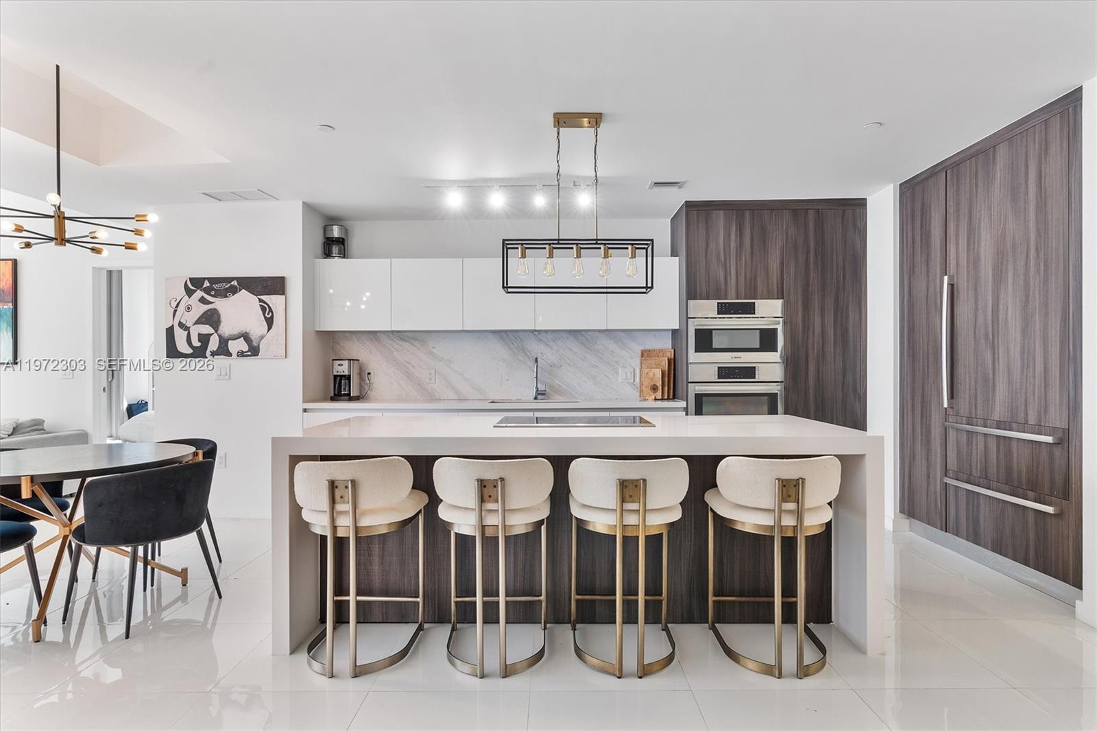 A modern kitchen features a white island with four stools, dark wood cabinetry, and marble backsplash — 851 NE 1st Ave # 1712, Miami FL 33132, MIAMI, FL