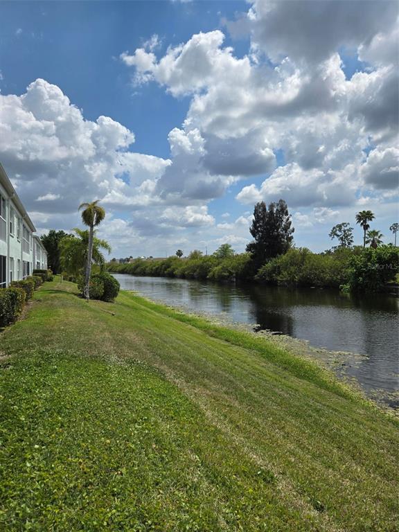 A grassy lawn slopes down to a canal beside a multi-story apartment building — 5725 GREENWOOD AVENUE UNIT 5201, NORTH PORT, FL