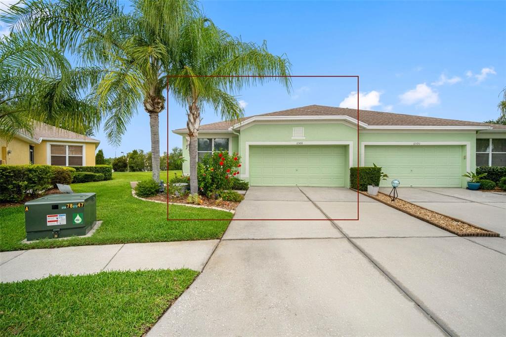 The exterior of a light green duplex home features a two-car garage and palm tree — 11588 CAPTIVA KAY DRIVE, RIVERVIEW, FL