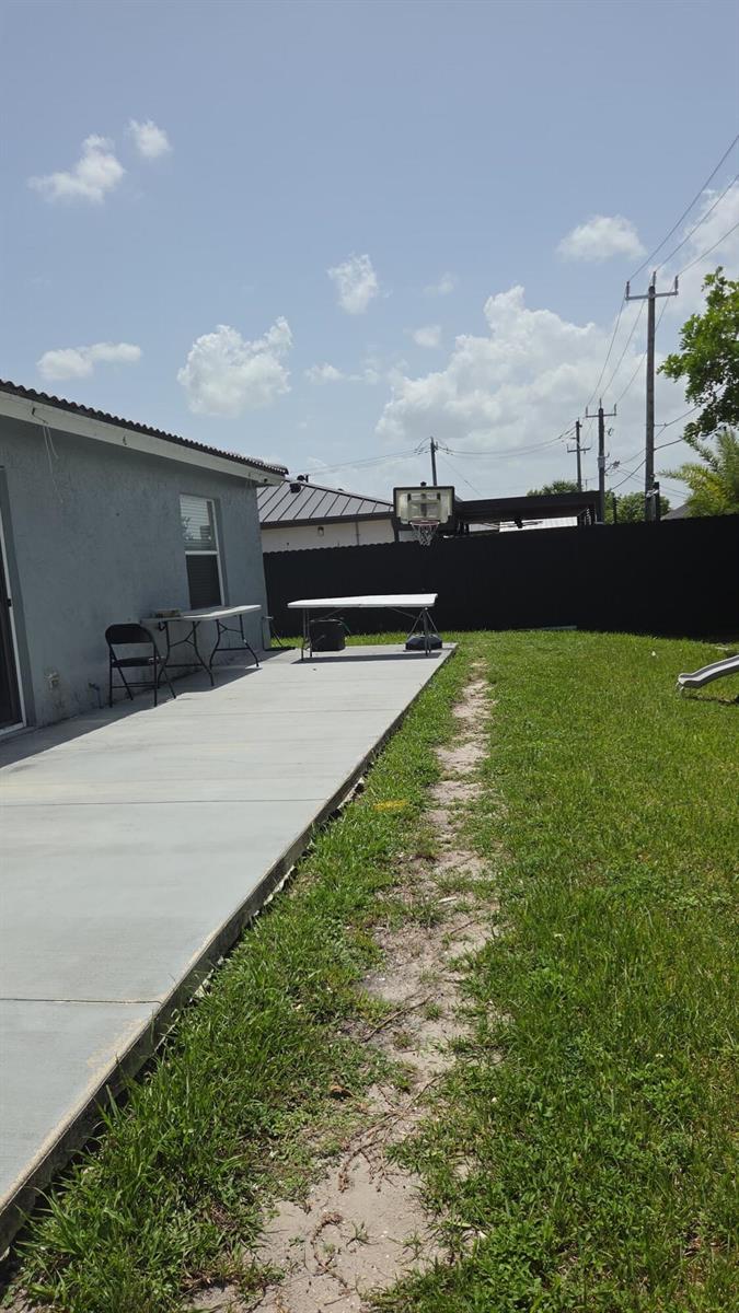 A concrete patio extends from the side of a house into a grassy backyard — 8221 NW 45TH Street, Lauderhill FL 33351, LAUDERHILL, FL