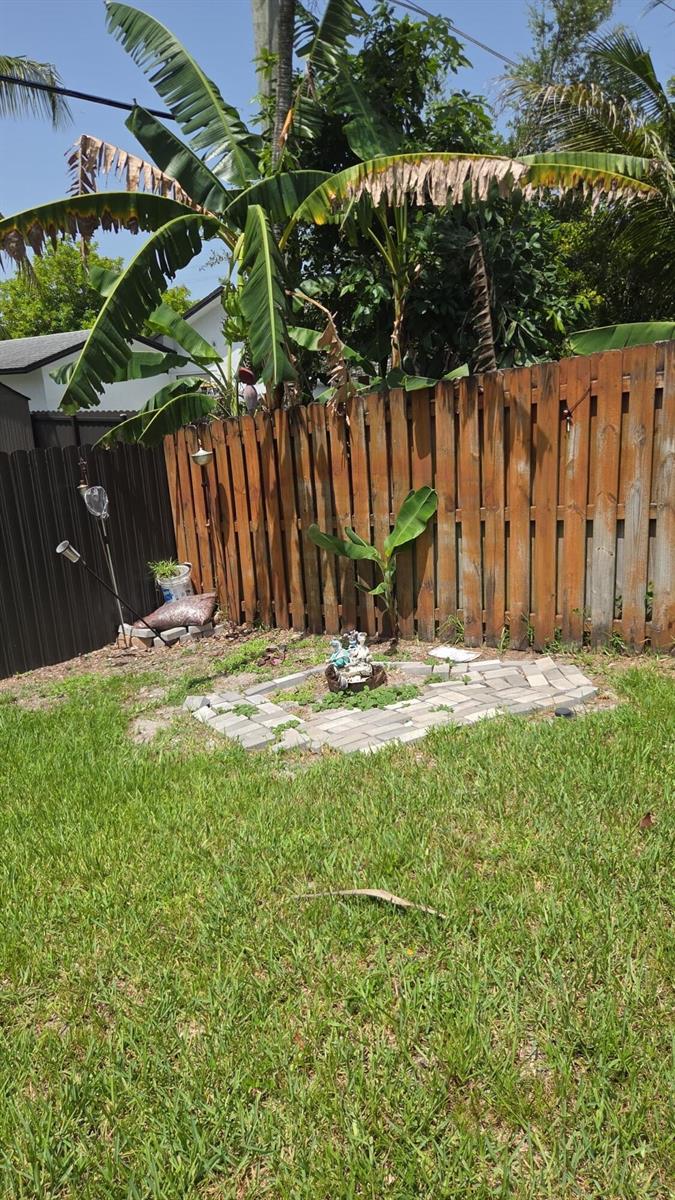A backyard features a small paver patio, a banana tree, and a wooden privacy fence — 8221 NW 45TH Street, Lauderhill FL 33351, LAUDERHILL, FL