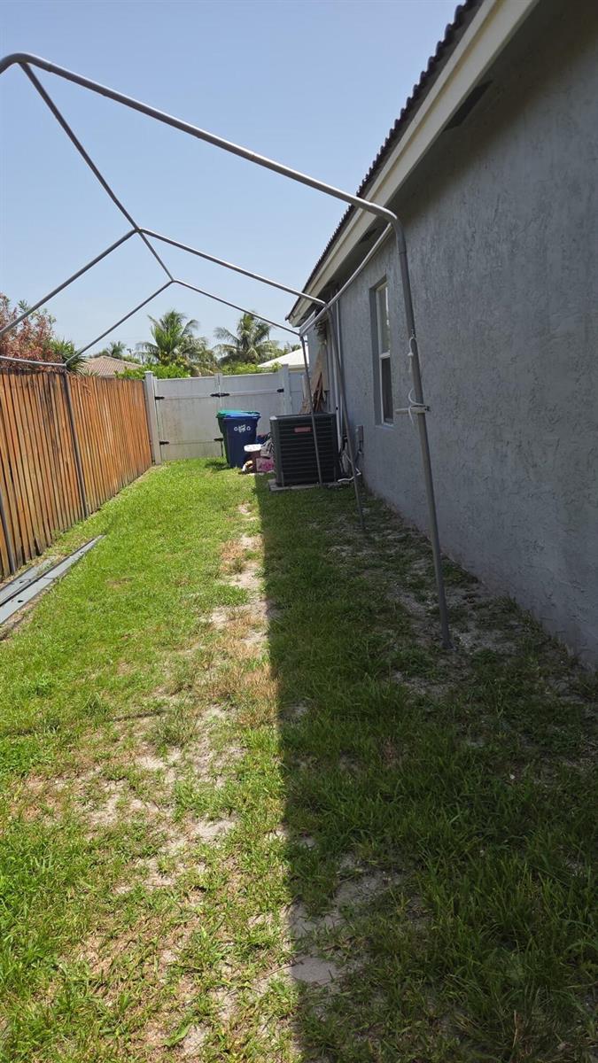 A narrow side yard features a metal canopy frame, a wooden fence, and an AC unit — 8221 NW 45TH Street, Lauderhill FL 33351, LAUDERHILL, FL