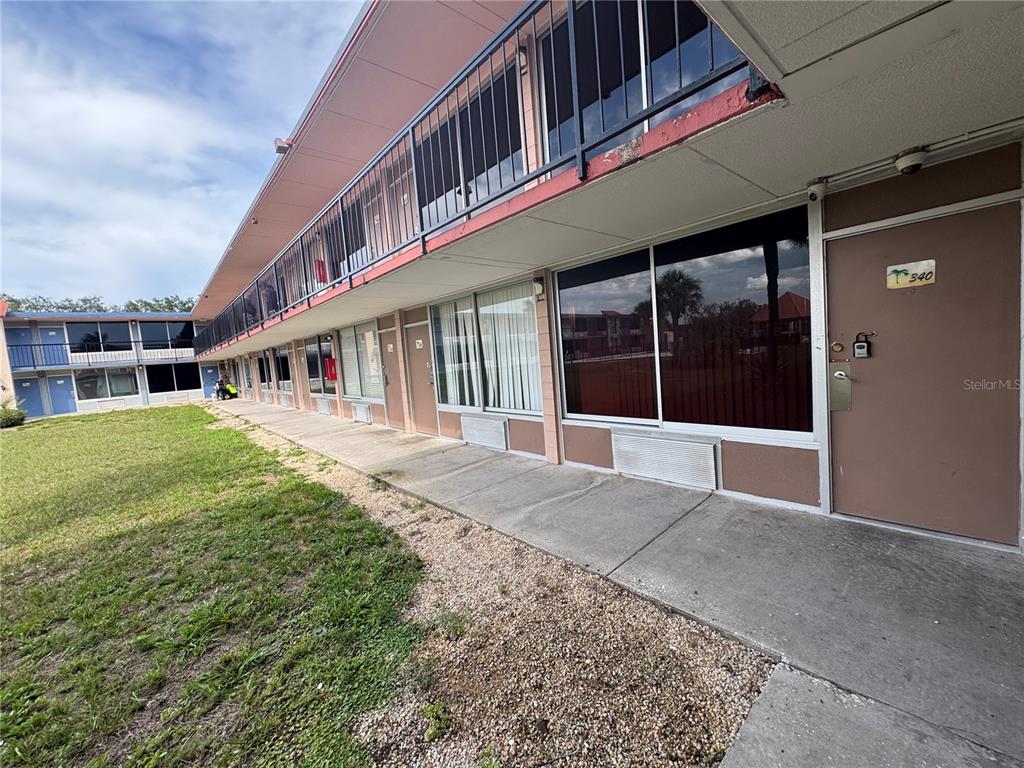 A multi-story motel exterior features a concrete walkway, brown doors, and large tinted windows — 43420 HIGHWAY 27 UNIT 340, DAVENPORT, FL