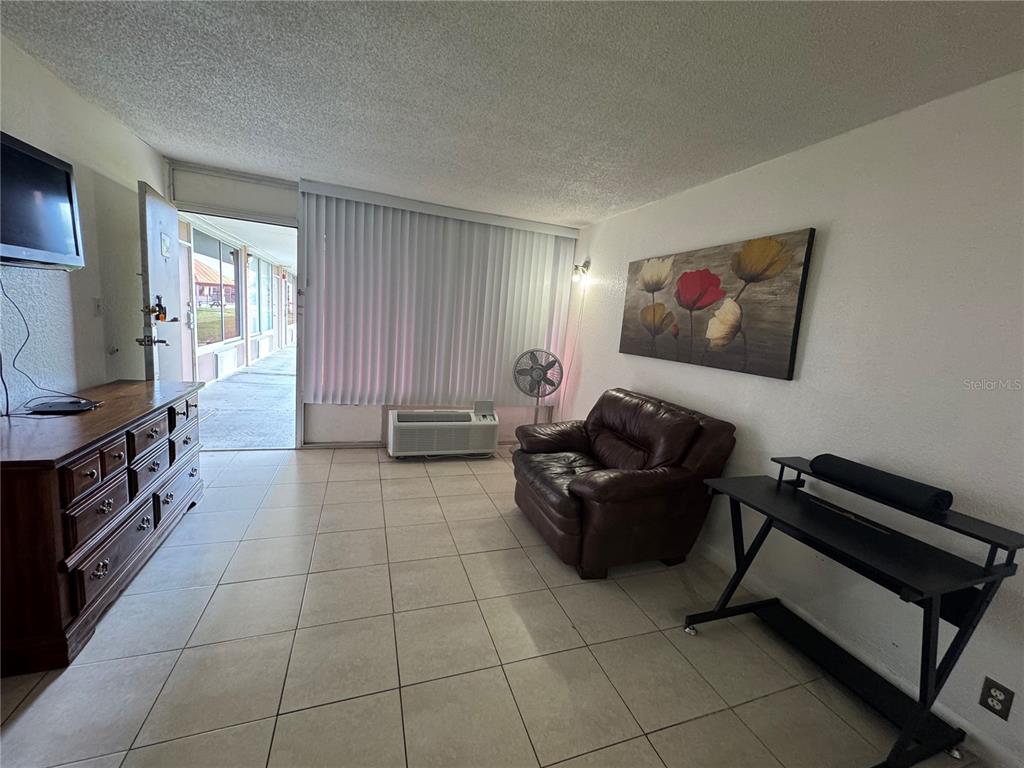 A living room features tile flooring, a brown leather armchair, a dresser, and a desk — 43420 HIGHWAY 27 UNIT 340, DAVENPORT, FL