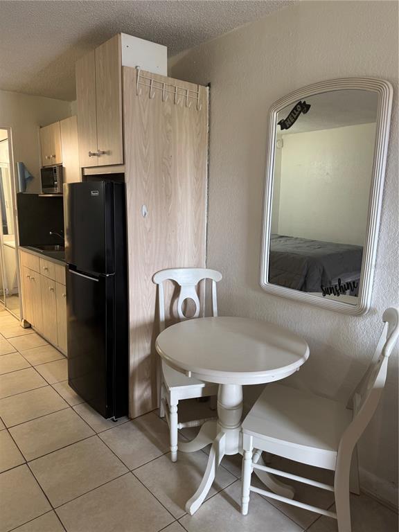 A small dining area with a round table and two chairs sits beside a black refrigerator — 43420 HIGHWAY 27 UNIT 340, DAVENPORT, FL