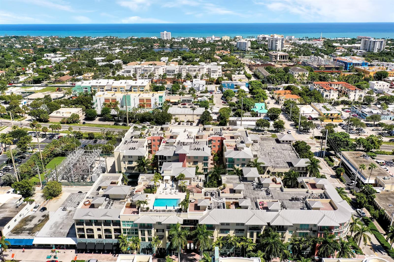 An aerial view shows a multi-story apartment complex with a rooftop pool and surrounding city — 235 NE 1st Street # 413, Delray Beach FL 33444, DELRAY BEACH, FL