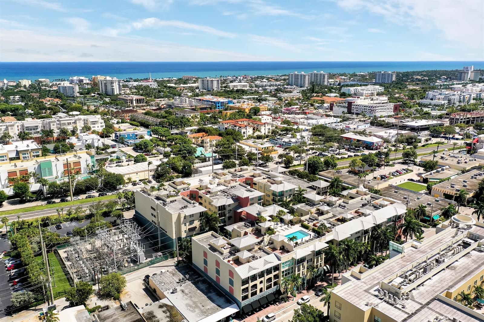An aerial view shows a multi-story residential complex with a pool near a coastal city — 235 NE 1st Street # 413, Delray Beach FL 33444, DELRAY BEACH, FL
