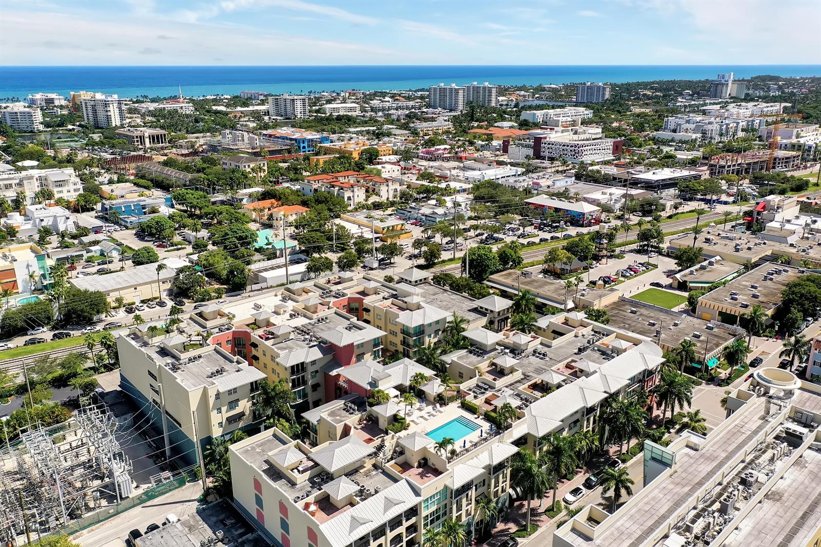 An aerial view of a multi-story apartment complex with a swimming pool and surrounding city — 235 NE 1st Street # 413, Delray Beach FL 33444, DELRAY BEACH, FL