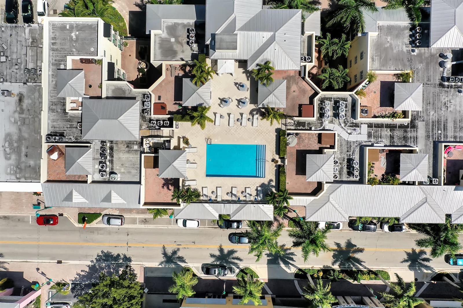 An aerial view shows a rectangular swimming pool surrounded by a patio and building rooftops — 235 NE 1st Street # 413, Delray Beach FL 33444, DELRAY BEACH, FL