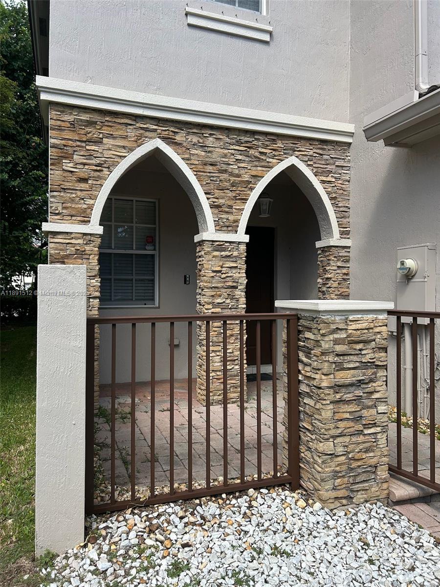 A stone-clad entryway features two pointed arches and a brown metal gate — 22066 SW 93rd Pl, Cutler Bay FL 33190, CUTLER BAY, FL