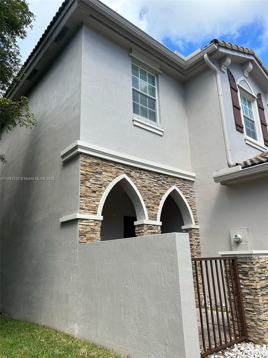 The exterior of a two-story house features stucco walls, stone accents, and arched entryways — 22066 SW 93rd Pl, Cutler Bay FL 33190, CUTLER BAY, FL