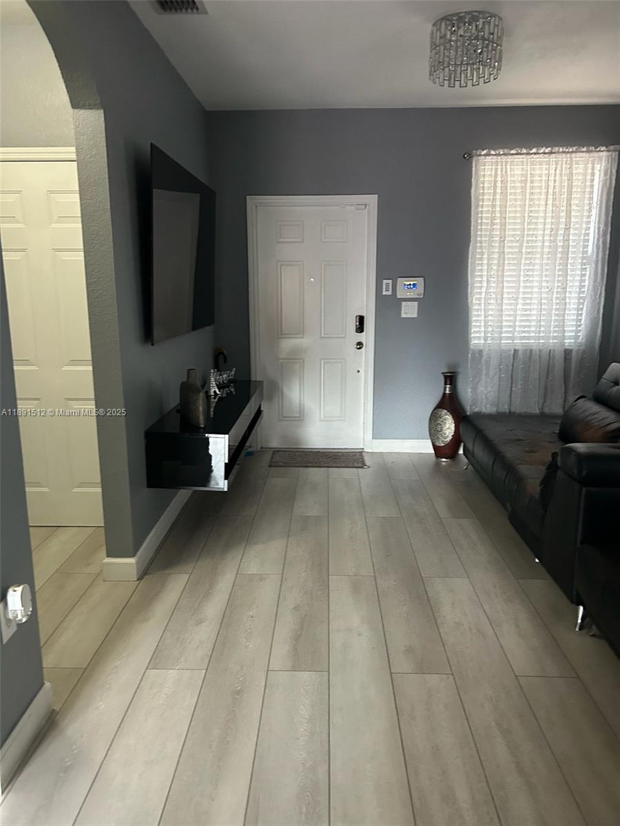 A living room features gray walls, light wood-look flooring, a black wall-mounted console, and furniture — 22066 SW 93rd Pl, Cutler Bay FL 33190, CUTLER BAY, FL