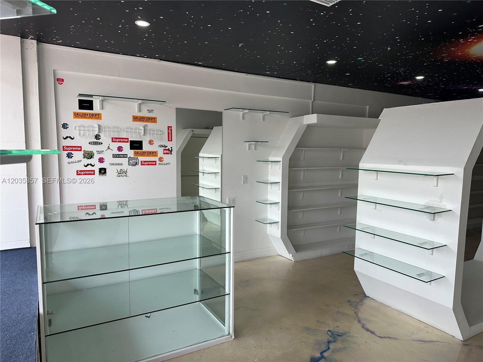 A retail space features glass display cases, white shelving units, and a starry ceiling mural — 142 Hialeah Dr, Hialeah FL 33010, HIALEAH, FL