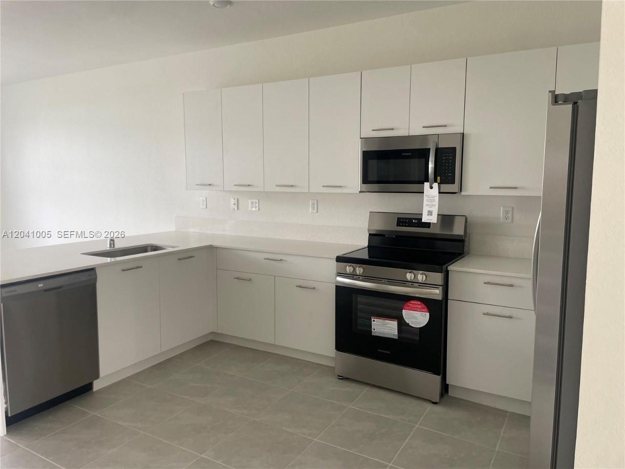 A kitchen features white cabinets, stainless steel appliances, and light-colored countertops — 12612 NW 22nd Pl # 12612, Miami FL 33167, MIAMI, FL