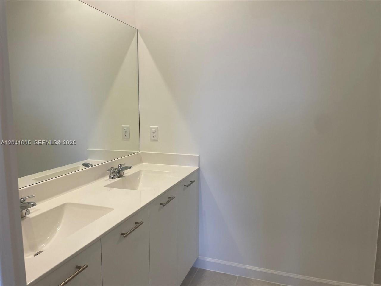 A bathroom features a double vanity with white cabinets, a large mirror, and light-colored countertops — 12612 NW 22nd Pl # 12612, Miami FL 33167, MIAMI, FL