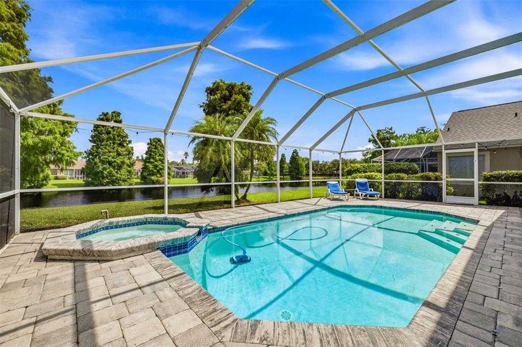 A screened-in swimming pool and hot tub overlook a lake behind a residential home — 10331 LIGHTNER BRIDGE DRIVE, TAMPA, FL