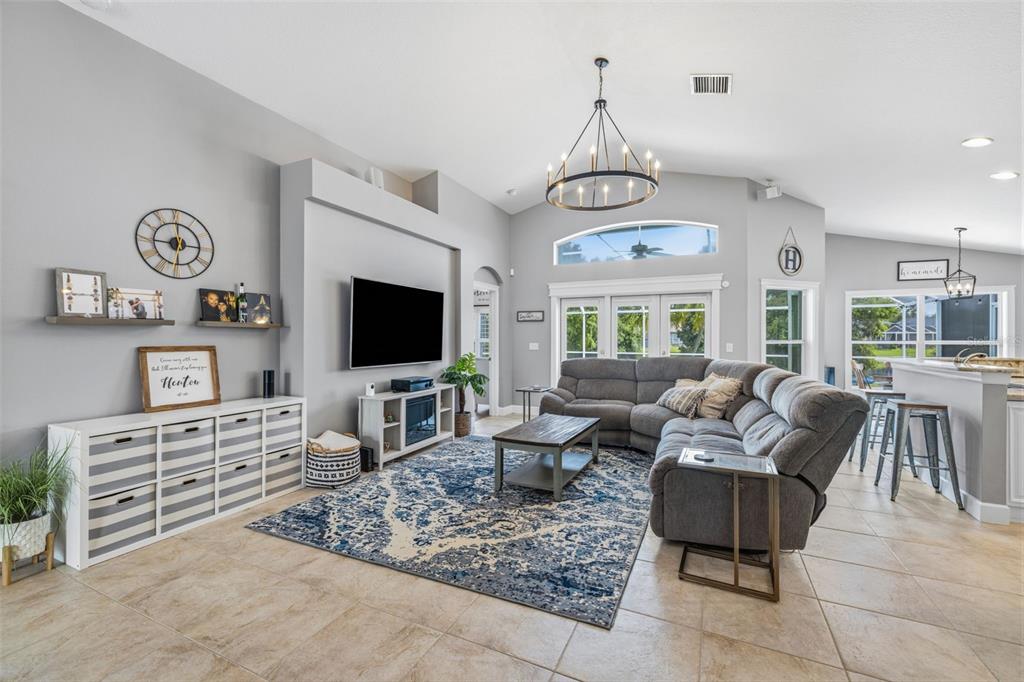 A living room features a gray sectional sofa, a blue patterned rug, and a television — 10331 LIGHTNER BRIDGE DRIVE, TAMPA, FL
