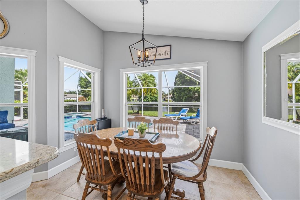 A dining area with a wooden table, spindle chairs, and large windows overlooking a pool — 10331 LIGHTNER BRIDGE DRIVE, TAMPA, FL