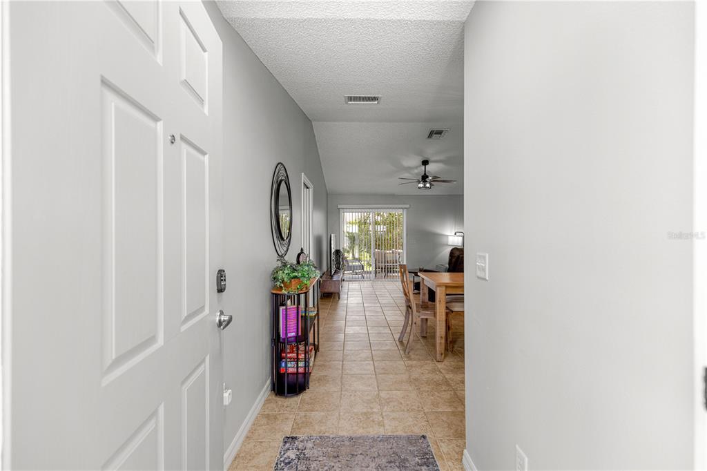 An entryway leads into a tiled living area with a dining table and sliding glass doors — 2180 JASPER WAY, THE VILLAGES, FL