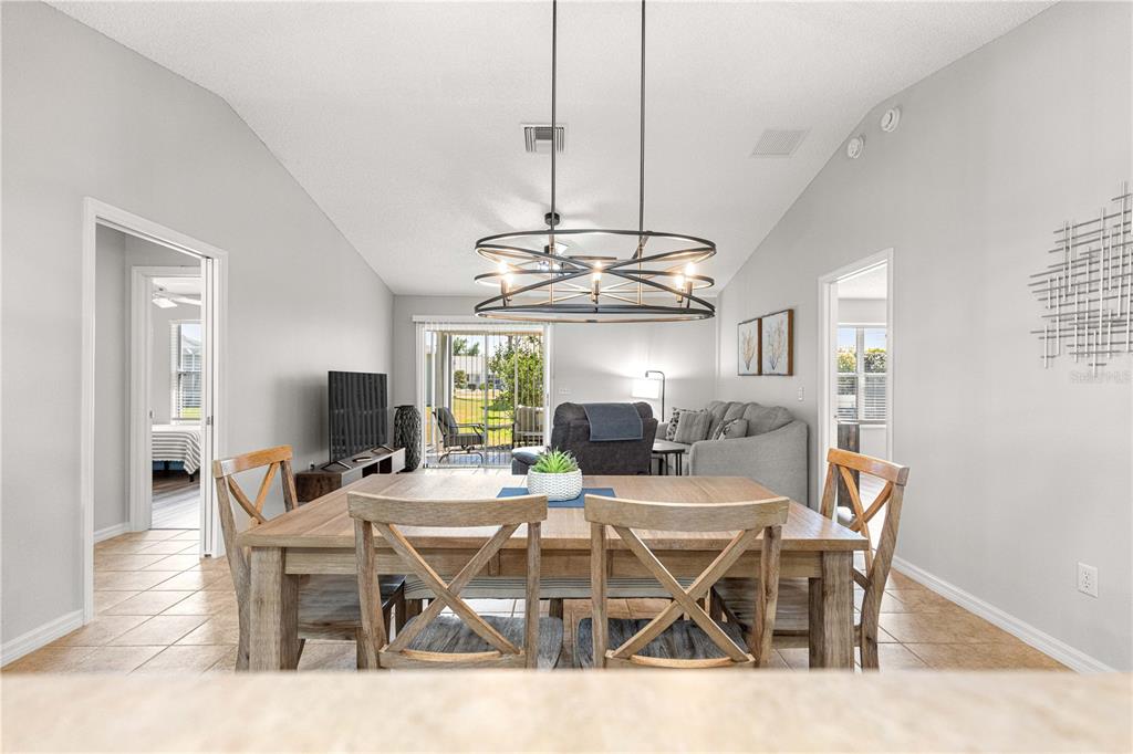 A dining area with a wooden table and chairs sits in front of a living room — 2180 JASPER WAY, THE VILLAGES, FL