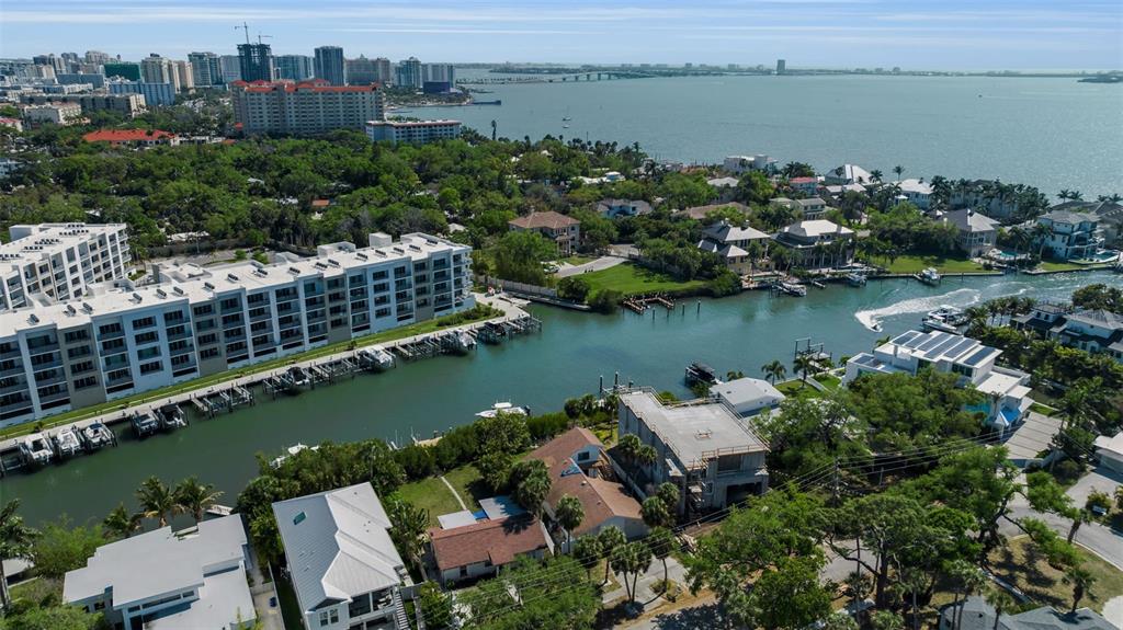 An aerial view shows a waterfront neighborhood with residential buildings, a canal, and a bay — 1040 SYLVAN DRIVE, SARASOTA, FL
