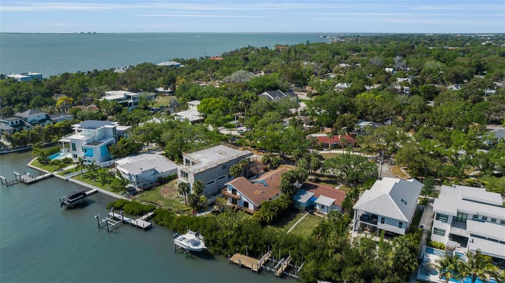 An aerial view shows waterfront homes with docks, boats, and lush trees along a bay — 1040 SYLVAN DRIVE, SARASOTA, FL
