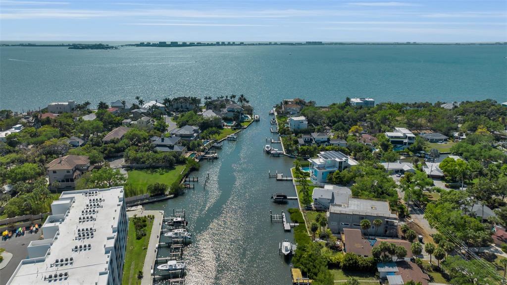 An aerial view shows a canal leading into a large bay surrounded by waterfront homes — 1040 SYLVAN DRIVE, SARASOTA, FL