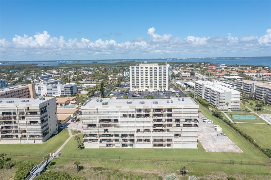 An aerial view shows several multi-story apartment buildings surrounded by green lawns and parking lots — 1890 N ATLANTIC AVENUE UNIT A302, COCOA BEACH, FL
